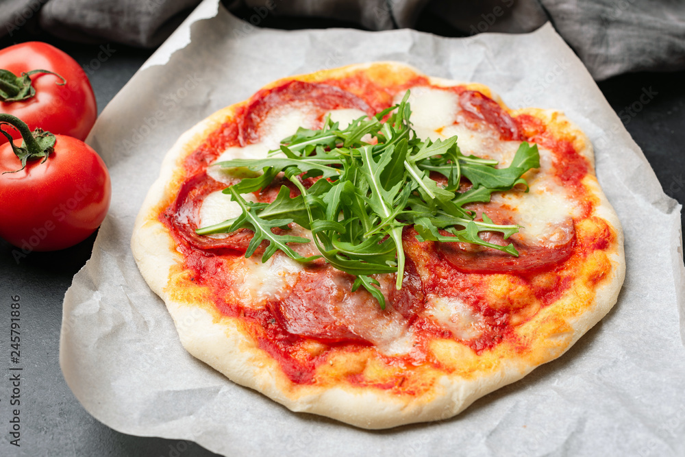 Tasty Pizza With Salami, Tomato Sauce, Cheese and Arugula. Selective focus
