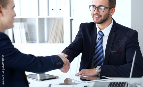 Business handshake at meeting or negotiation in the office. Two businessmen partners are satisfied because signing contract or financial papers