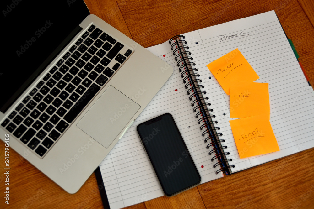 Flat lay style image with laptop computer, note paper and pen. Black phone / tablet used to help create lists. Flat lay style image with laptop computer, note paper and pen. Black phone / tablet used to help create lists.