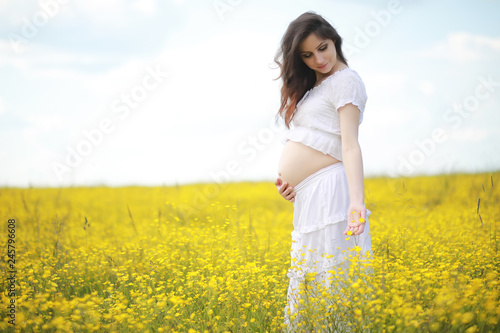 Pregnant woman in a dress in a field of flowers