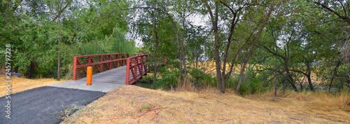 Views of Jordan River Trail Pedestrian and Train Track Bridge with surrounding trees, Russian Olive, cottonwood and muddy stream along the Wasatch Front Rocky Mountains, in Salt Lake City, Utah. photo