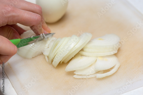 Girl's hand with a knife cutting onions on wooden Board