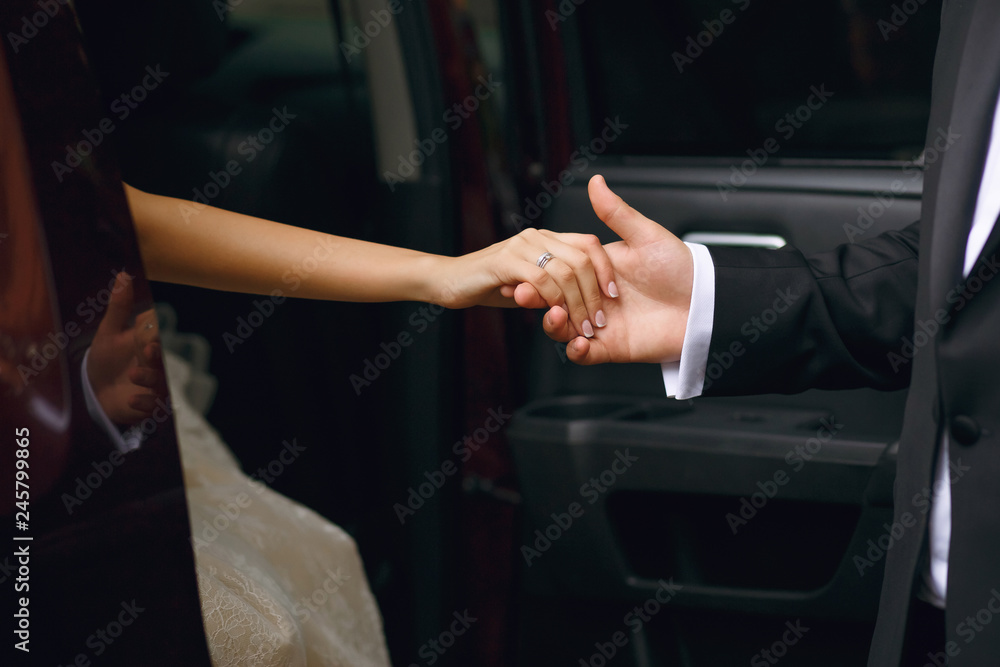 The groom gives his hand to the bride when she gets out of the car