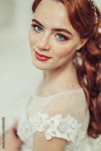 Close up portrait of young ginger bride with freckles in fashionable wedding dress