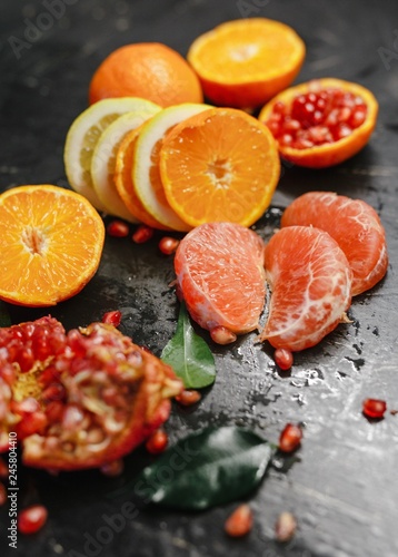 Slices of grapefruit  lemon and pomegranate in the black background.
