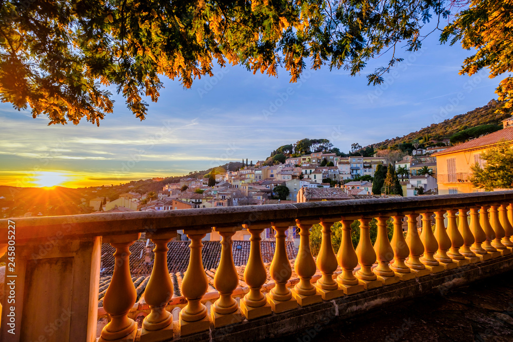 Vue panoramique sur le village de Bormes-les-Mimosas depuis la terrasse. Arbres de mimosa en fleurs. Coucher de soleil. Provence, France.