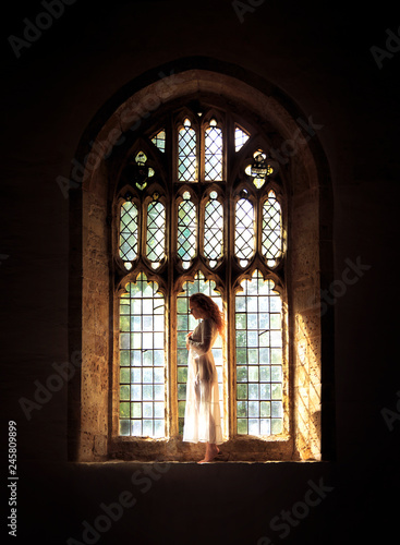 Beautiful woman posing in a Gothic church stained glass window