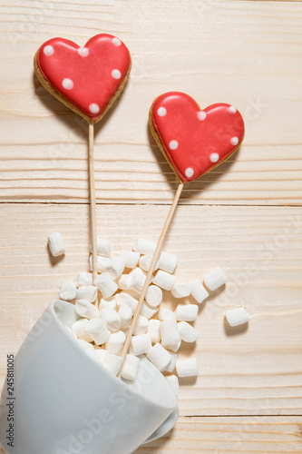 Photo of gingerbread in the form of a heart with marshmallows and a cup on a wooden background. Photos for the day of lovers. Love, mother's day, birth of a child. Background for blog 
