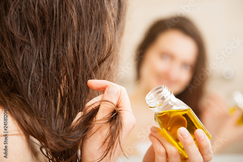 Young woman spreading oil mask over her hair