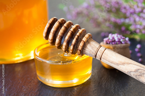 Fresh natural honey, wooden honey dipper and heather flowers