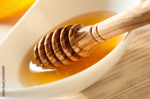 Honey dipper in a porcelain bowl with fresh honey