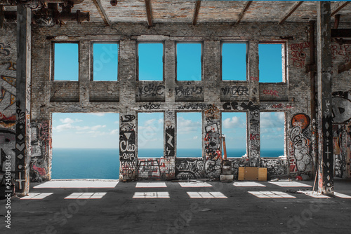 Fototapeta Opuszczone ruiny fabryki / loft magazynowy z oknami i tłem oceanu i błękitnego nieba
