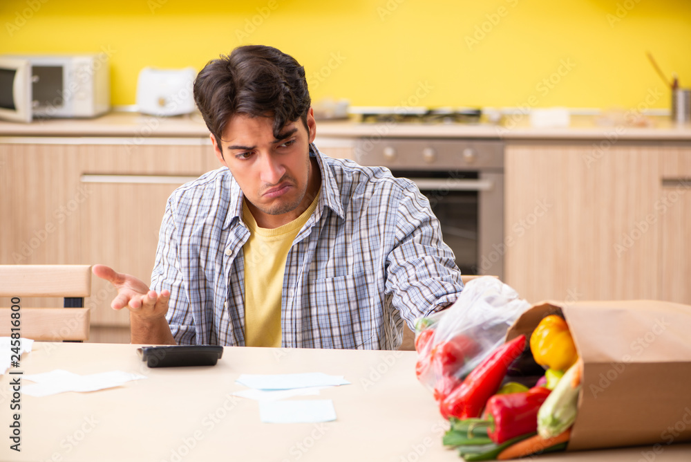 Young man calculating expences for vegetables in kitchen Young man calculating expences for vegetables in kitchen