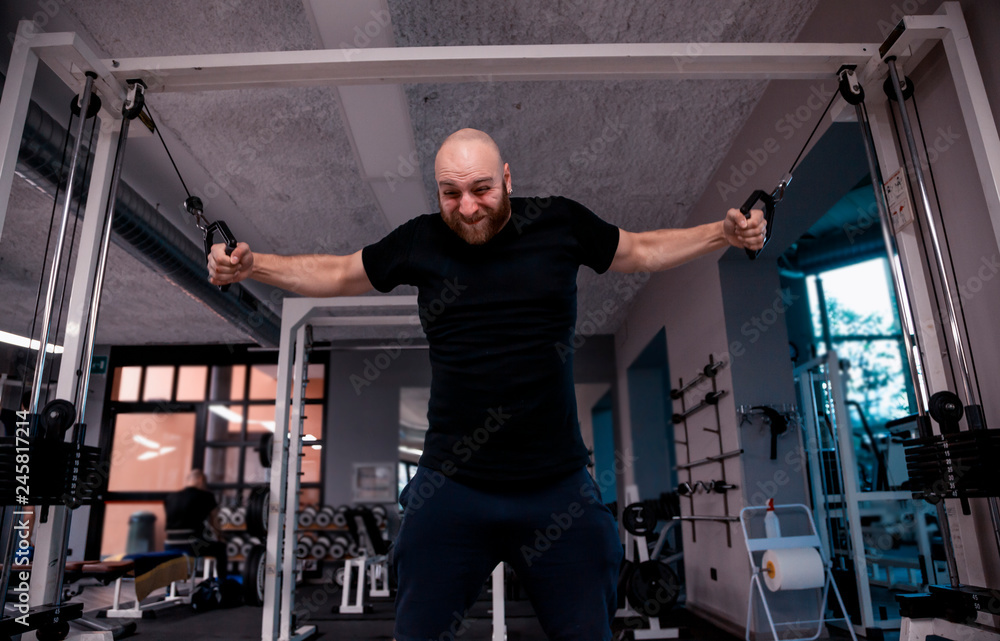 athlete while doing heavy exercises at the cables athlete while doing heavy exercises at the cables