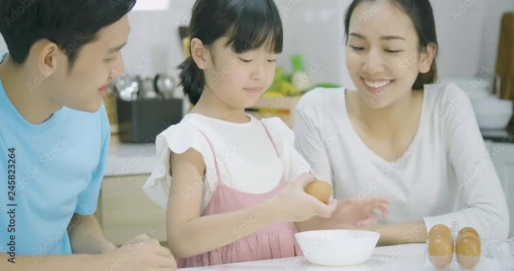 Smiling asian father, mother and daughter enjoys preparing a healthy dinner in the kitchen together. Mother teaching her daughter to cooking. Smiling asian father, mother and daughter enjoys preparing a healthy dinner in the kitchen together. Mother teaching her daughter to cooking.