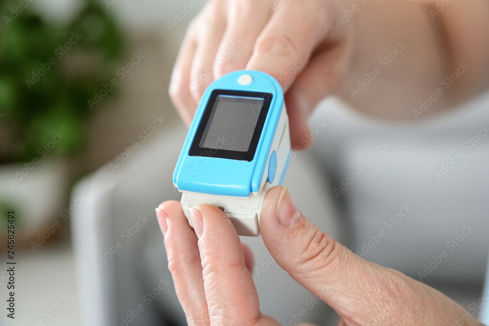Mature woman checking pulse with medical device at home, closeup Mature woman checking pulse with medical device at home, closeup