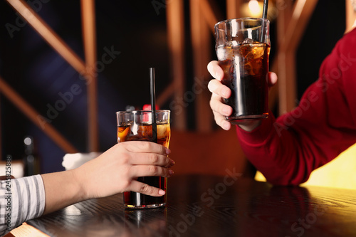 Young couple with glasses of refreshing cola at table indoors  closeup