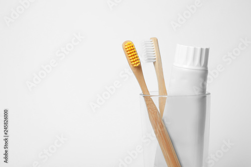 Glass with brushes and toothpaste on white background. Space for text