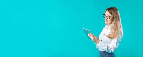 Portrait young caucasian woman worker teacher trainer mentoring in white shirt office style long hair with a tablet in hand uses technology isolated bright color blue background