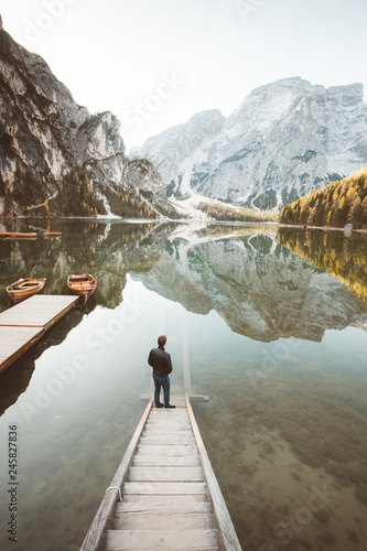 Young man watching sunrise at Lago di Braies, South Tyrol, Italy