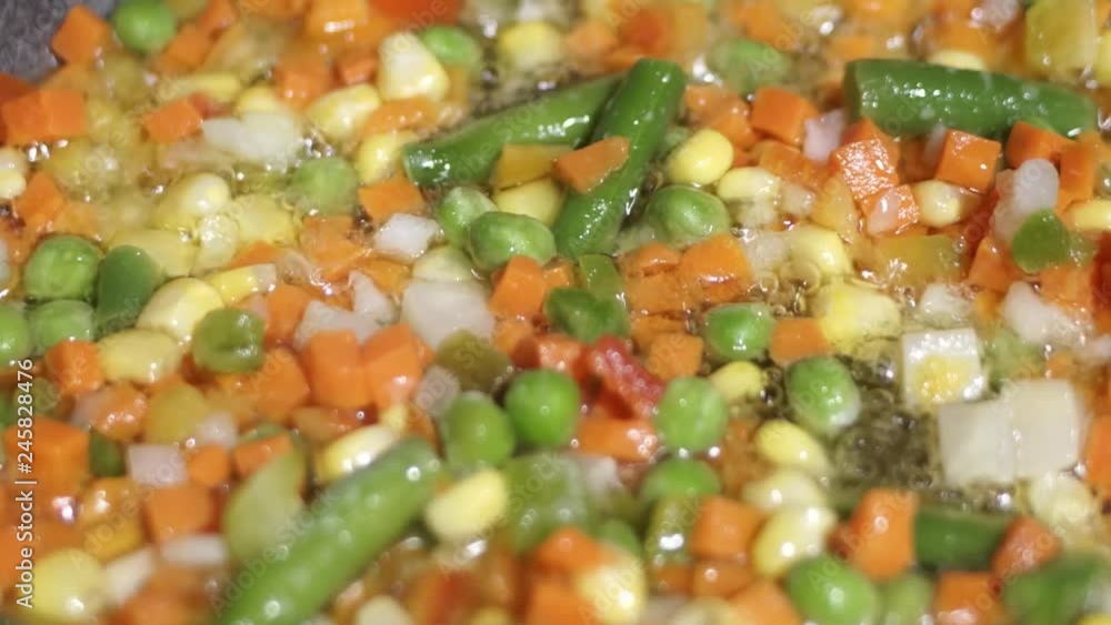 Close-up of frozen mixed vegetables in a pan. Frying vegetables for dinner. Close-up of frozen mixed vegetables in a pan. Frying vegetables for dinner.