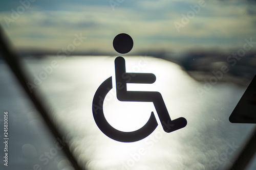 Disable wheelchair sign in public transportation on door glass with the background of sun reflection in the ocean sunset time in Japan, important and care of disable in developed country photo