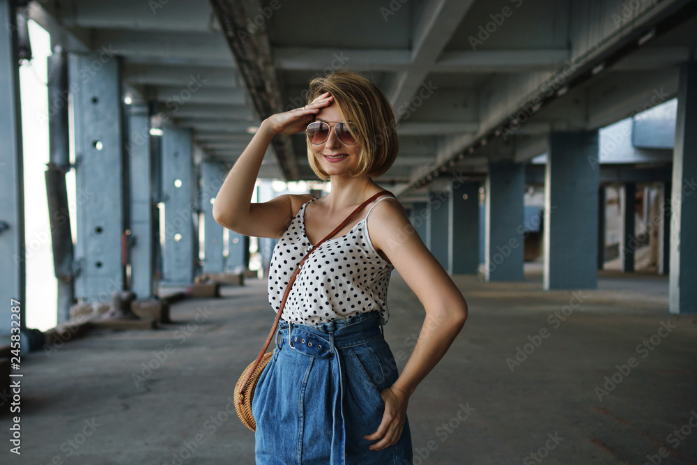 Young attractive girl in sunglasses with handbag outdoors in urban environment. Spring mood. Portrait Young attractive girl in sunglasses with handbag outdoors in urban environment. Spring mood. Portrait