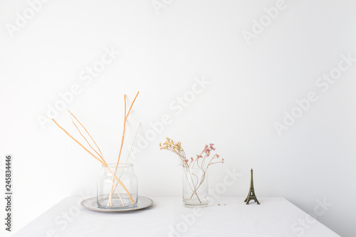 Glass vase of dried flower plant an eiffel tower miniature on white table top...