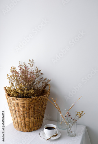 Dried plant and flower in rattan wooden basket on white table top and a white...