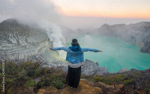 Back view of young woman standing on the crater of Kawah Ijen volcano in East Java, Indonesia.