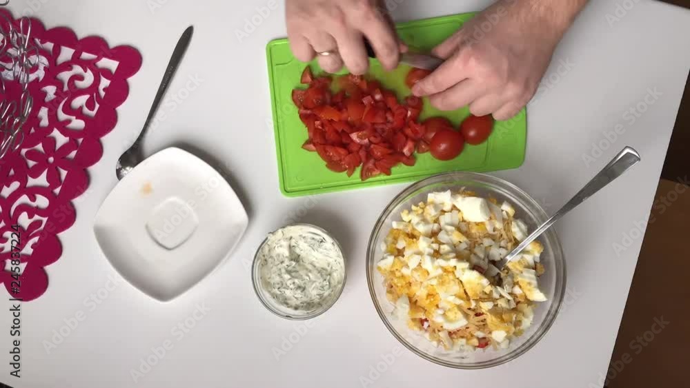 A man slices tomatoes on a cutting board. Cooking salad of crab sticks, cheese, eggs and tomatoes. TimeLapse. A man slices tomatoes on a cutting board. Cooking salad of crab sticks, cheese, eggs and tomatoes. TimeLapse.