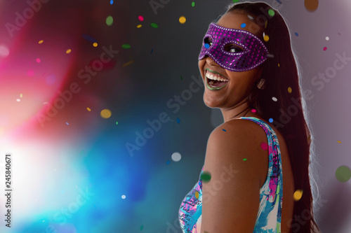 Fototapeta Naklejka Na Ścianę i Meble -  people, holidays, emotion and carnival concept - happy young woman with mask and confetti at carnaval party. Carnaval concept