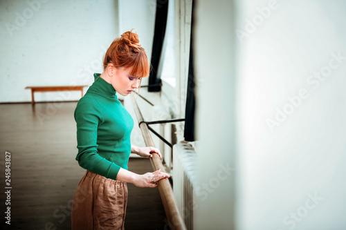 Red-haired professional ballet dancer with hair bun looking concentrated