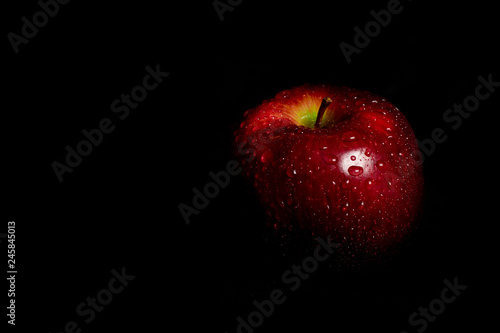 full apple with water drops on black background 