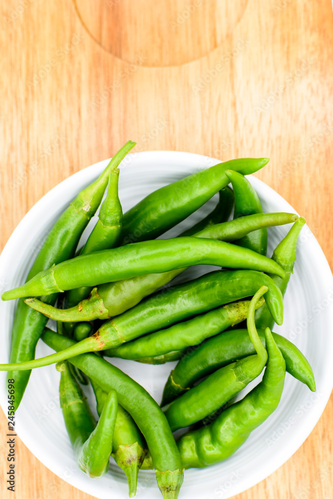 green chilies in bowl on wooden table green chilies in bowl on wooden table