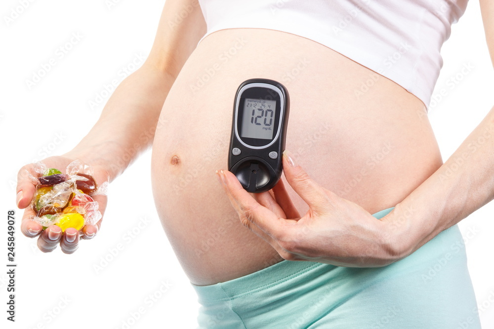 Woman in pregnant with glucometer and colorful candies, diabetes and healthy nutrition during pregnancy Woman in pregnant with glucometer and colorful candies, diabetes and healthy nutrition during pregnancy