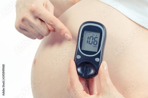 Pregnant woman showing glucometer with result of measurement sugar level, diabetes during pregnancy