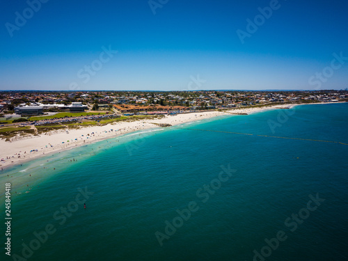 Drone photo of beach and water in summer with people swimming, blue sky