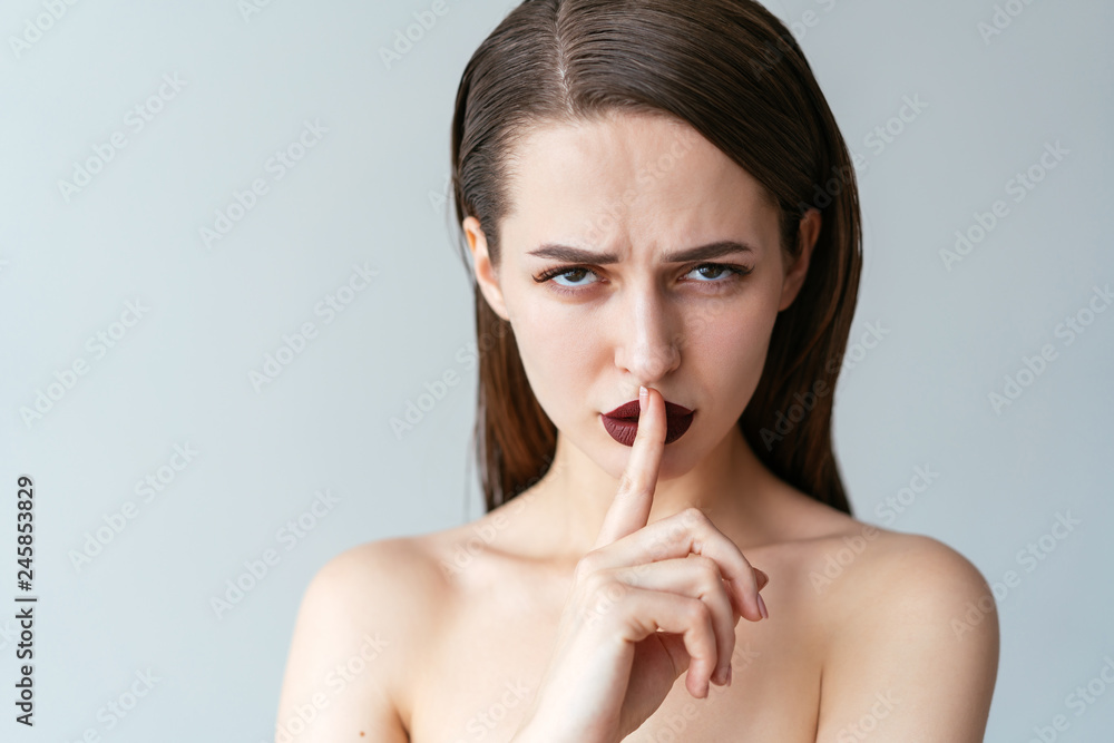 Pretty woman showing silence sign holding finger on lips Pretty woman showing silence sign holding finger on lips