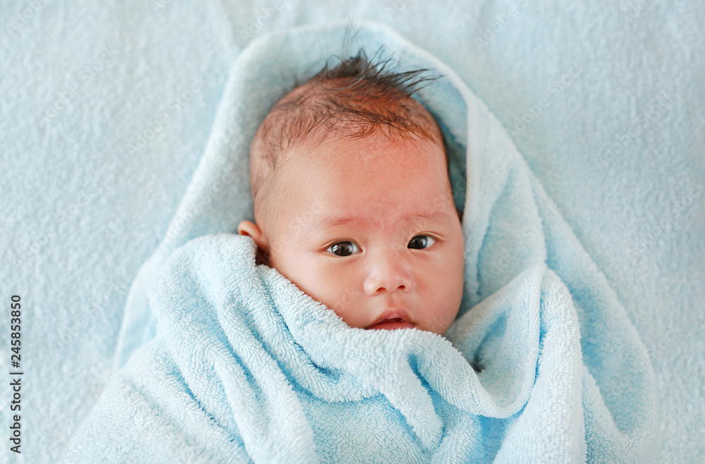 Closeup Infant baby boy in towel roll looking at camera lying on bed after bath. Closeup Infant baby boy in towel roll looking at camera lying on bed after bath.