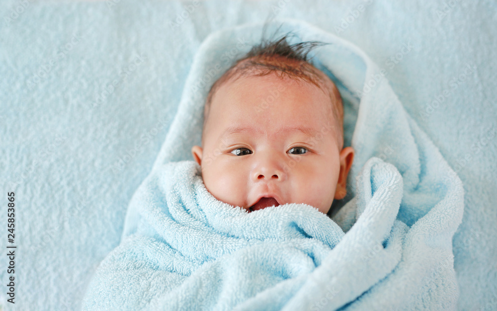 Closeup Infant baby boy in towel roll looking at camera lying on bed after bath. Closeup Infant baby boy in towel roll looking at camera lying on bed after bath.