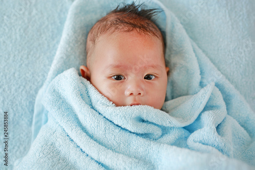 Portrait of cute infant baby boy in towel lying on bed after bath.  © zilvergolf