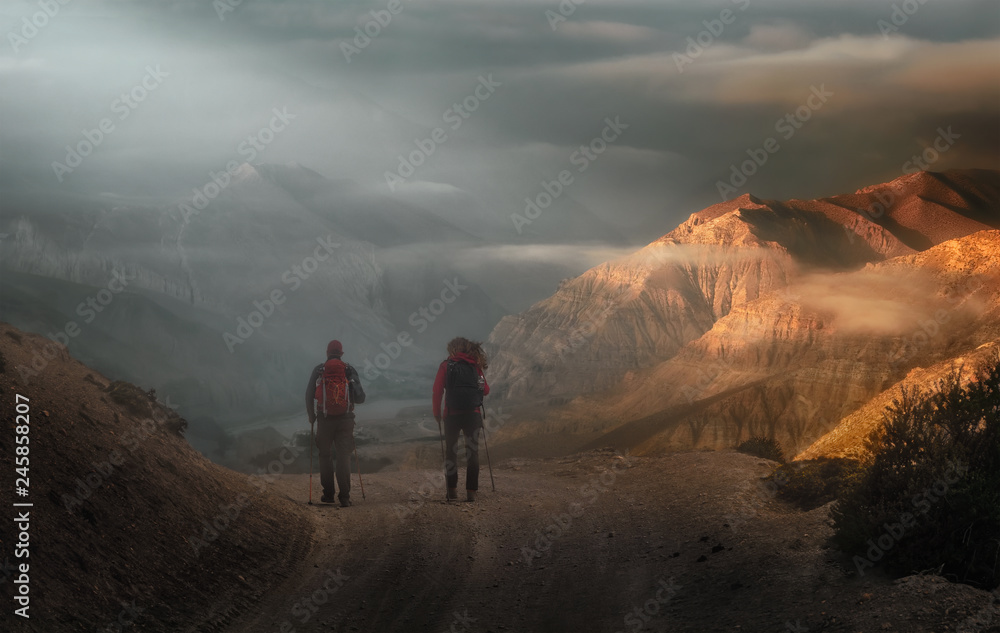 Obraz premium Two hikers with backpacks go high in the mountains of the Nepal.