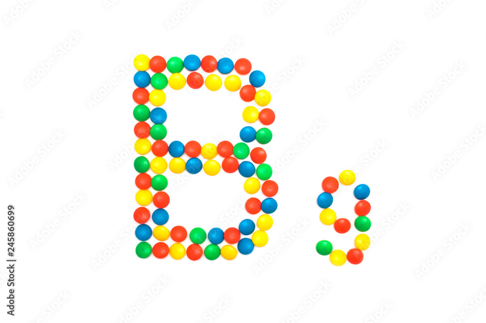 Multi-colored vitamins pills that are lined with the letter Vitamin group B9, close-up
