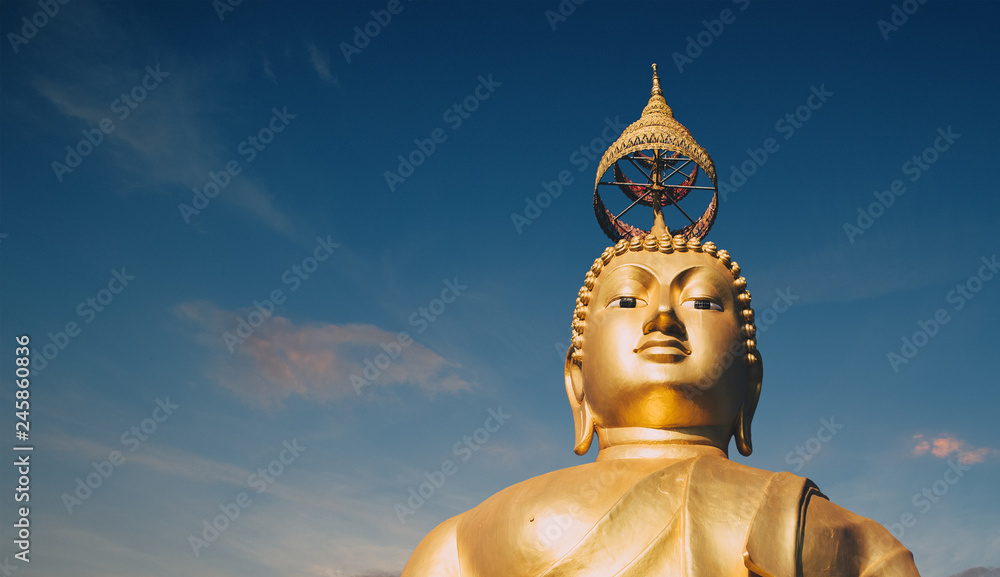 Big gold Buddha statue at the sunrise in Tiger Cave Temple in Krabi province, Thailand