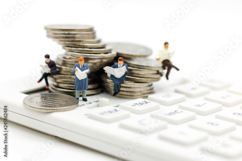 Miniature people: Businessman reading book on calculator and coins, Business and finance investment concept photo