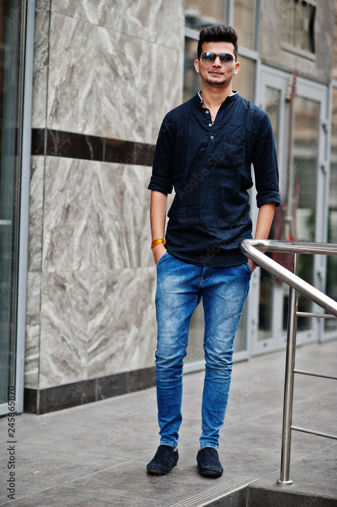 Stylish indian model man in casual clothes and sunglasses posed outdoor at street of India. Stylish indian model man in casual clothes and sunglasses posed outdoor at street of India.