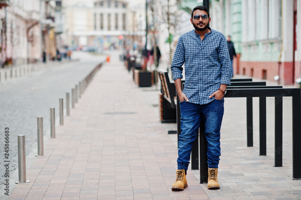 Stylish indian beard model man in casual clothes posed outdoor at street of India.