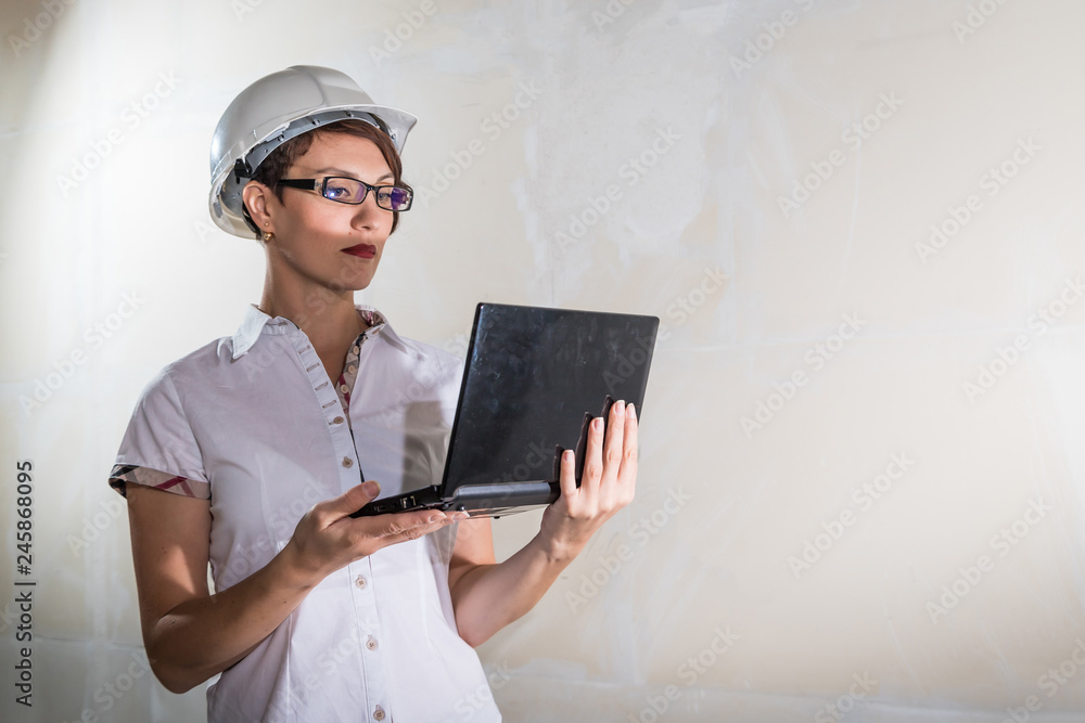 Cute young woman in white construction protection building helmet in unfinished apartment Cute young woman in white construction protection building helmet in unfinished apartment