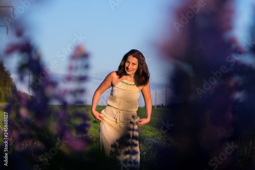Nice woman in a green field and purple lupines